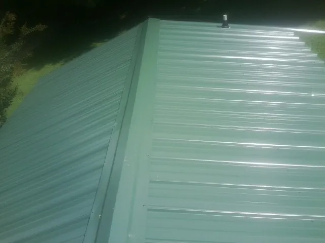 New green metal panels meeting at the ridge of a roof — Flat Roof Repair work by our crew in Kemp