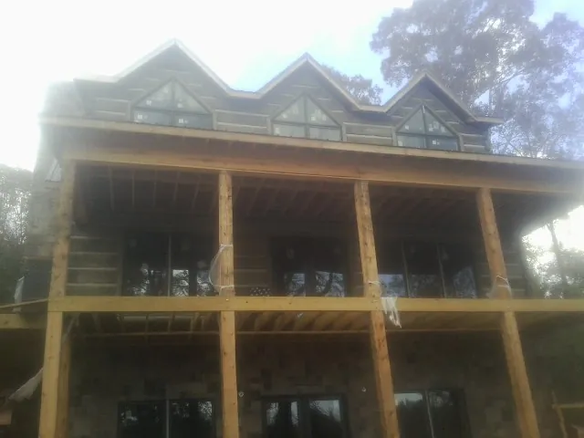 Dormers and porch framing on a large log home under construction — Roof Coating work by our crew in Kemp