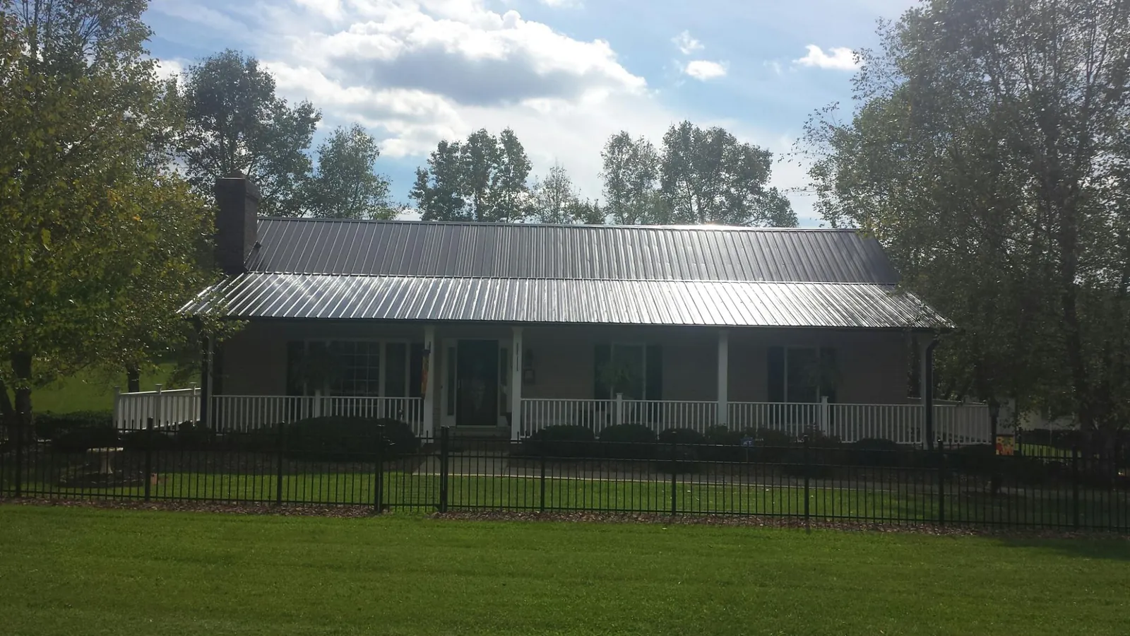 Gray metal roof on a brick ranch with a full width front porch — Gutter Guard Installation work by our crew in Kemp