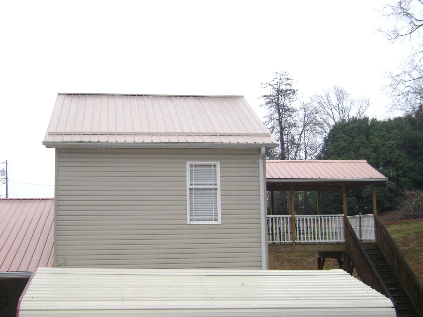 Tan metal roofs on a two story addition and attached porch, from a Roof Replacement job in Kemp