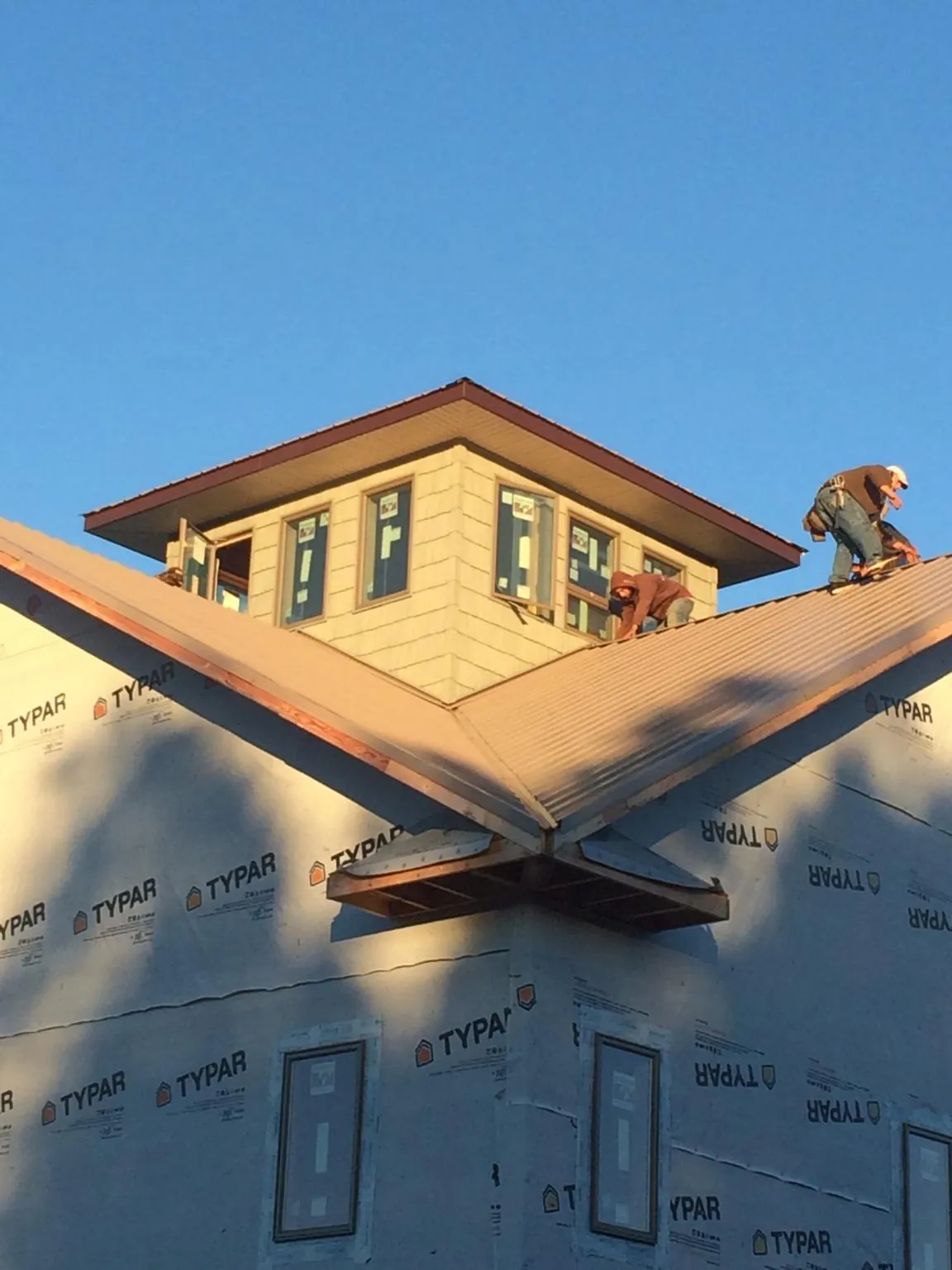 Roofers working around a rooftop cupola on a new metal roof at sunset — Roof Waterproofing in Kemp by Roofing Brothers